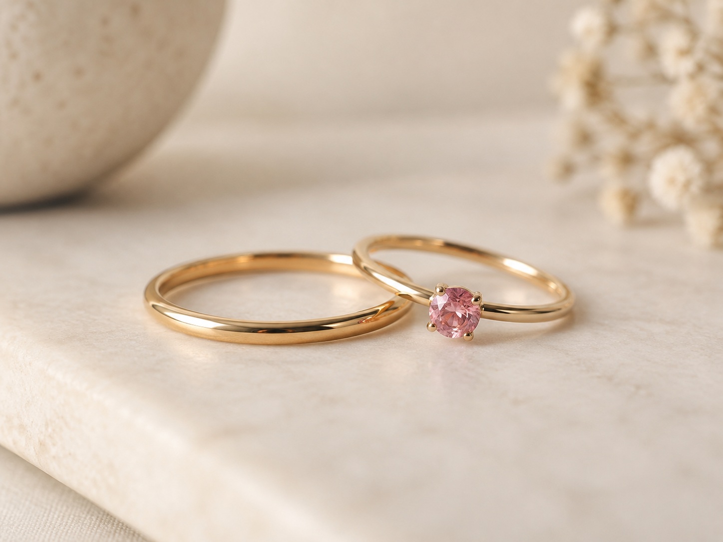 AI illustration of a plain band beside a small pink gemstone-style ring.