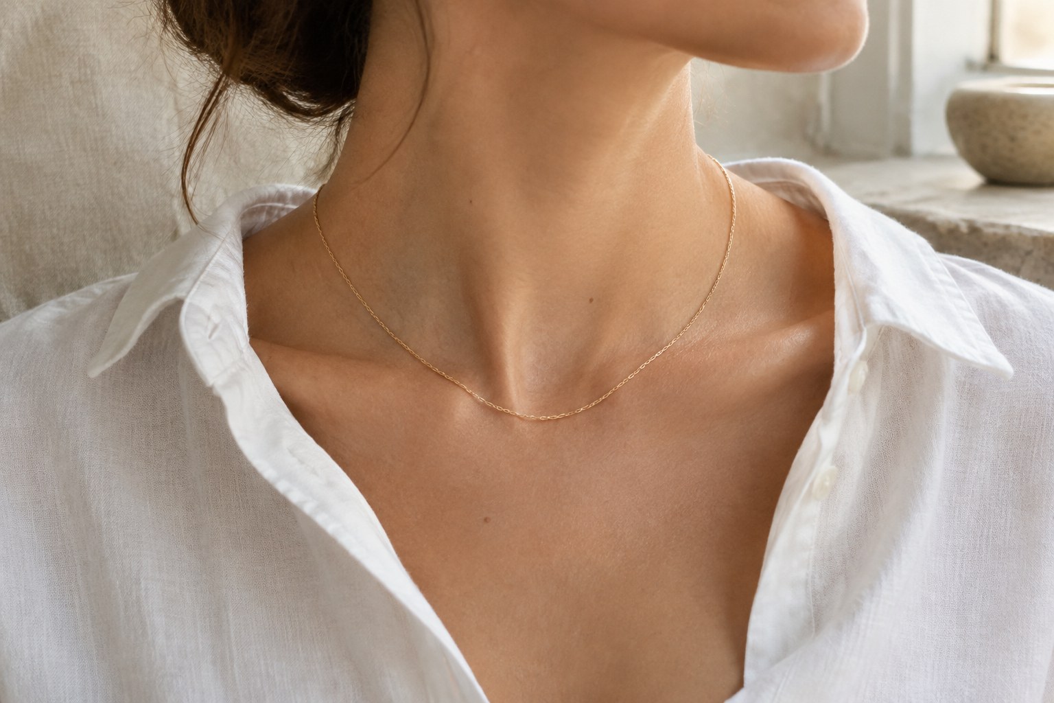 Illustration: a single fine gold chain at the collarbone
