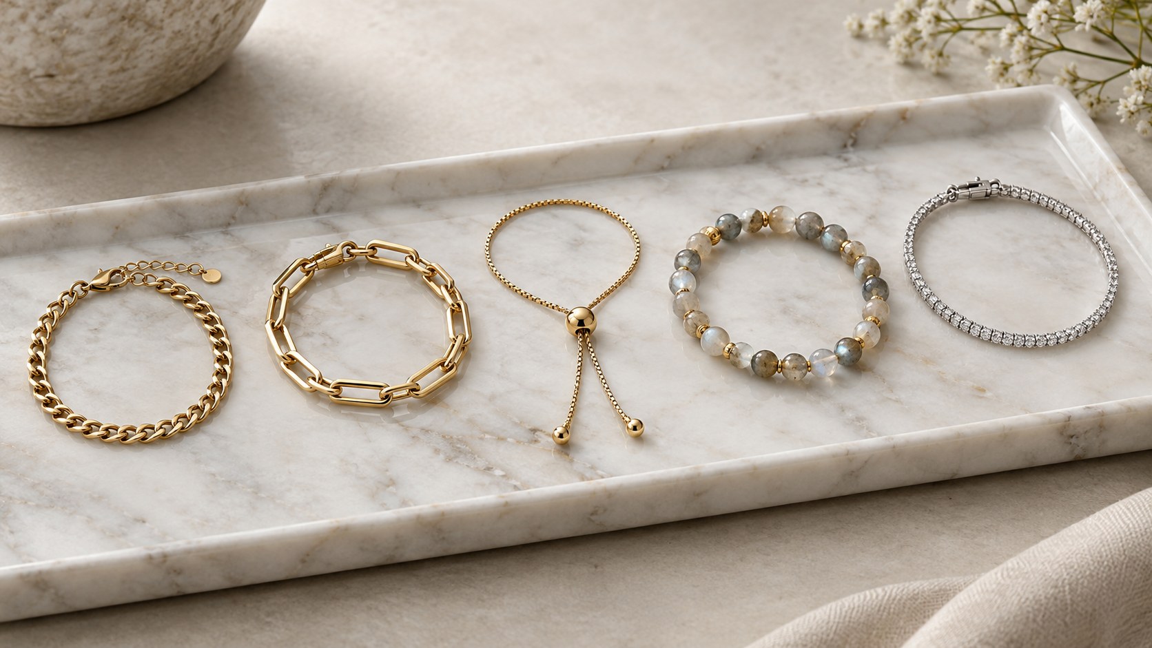 Chain, link, bolo, beaded and diamond line bracelets on a marble tray